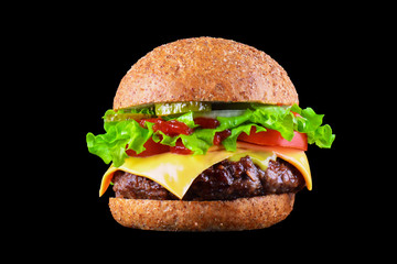 Big tasty hamburger or cheeseburger isolated on black background with grilled meat, cheese, tomato, bacon, onion. Burger closeup