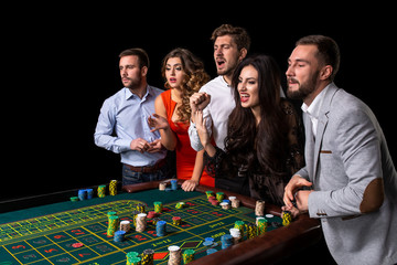 Group of young people behind roulette table in a casino