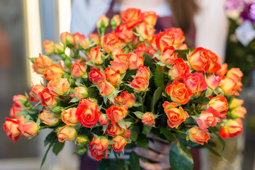 Young florist holding in her hands freshly made blossoming flower bouquet 