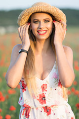 Pretty young sexy blonde in a hat on a poppy field