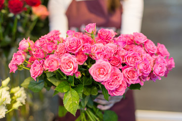 Young florist holding in her hands freshly made blossoming flower bouquet