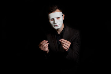 Portrait of a man in a white mask on a black background. Shows a gesture of money. Requires money