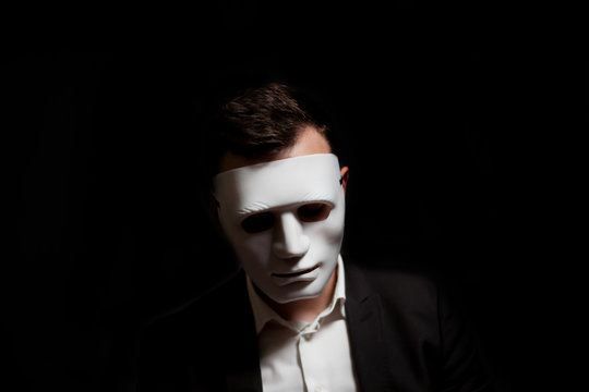 Close-up of a man in a white mask on a black background