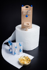 Wooden toy toilet, pills and paper on black background