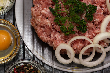 Raw meat beef in a plate with spices on a black cutting board. Fresh stuffing.