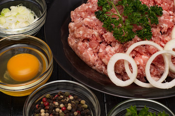 Raw meat beef in a plate with spices on a black cutting board. Fresh stuffing.