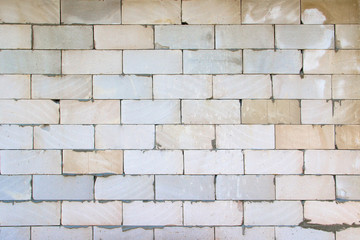 Wall from blocks of different shades with concrete seams, chips, scratches and stains.