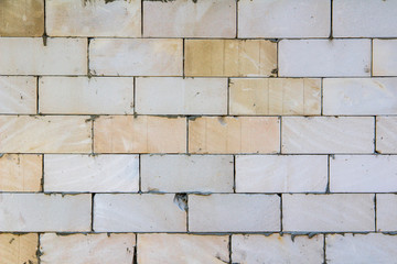 Wall from blocks of different shades with concrete seams, chips, scratches and stains.