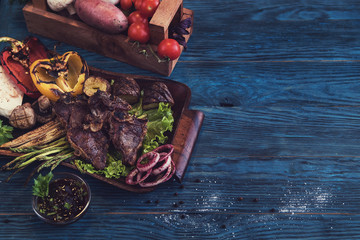 Grilled beef meat with vegetable on a blue wooden background
