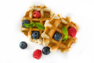 Traditional belgian waffles with blueberries and raspberries, isolated on white background. Top view