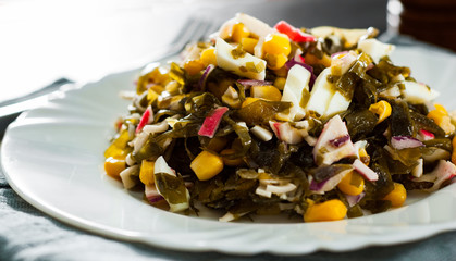 Seaweed Chuka sea kale salad with corn , crab sticks, eggs, onion on white plate on dark wooden table © pavel siamionov