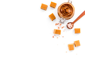 Contrast of flavors. The combination of salty and sweet. Caramel sauce in glass jar near caramel...