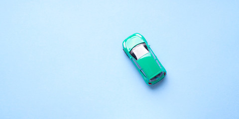 Green toy car on abstract blue background. Travel, purchase minimal concept