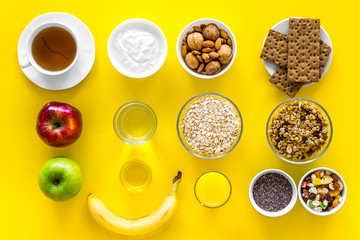 Layout of products for healthy and hearty breakfast. Fruits, oatmeal, yogurt, nuts, crispbreads, chia on yellow background top view copy space
