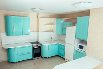 beautiful kitchen in turquoise colors with a refrigerator, microwave, table, stove and sink