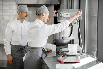 Confectioners working with kneader machine at the bakery manufacturing