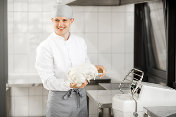 Portrait of a male baker mixing dough with professional kneader machine at the manufacturing