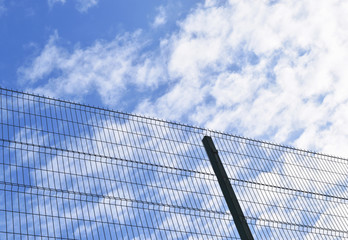 Metal fence and blue sky in the clouds.