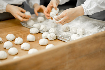 Forming daugh balls for baking buns on the wooden table at the manufacturing
