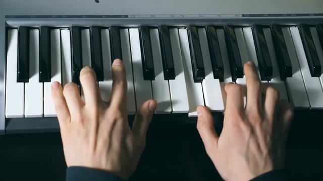Hands of male musician playing at synthesizer. Mens arms plays solo of music or new melody. Close up fingers of pianist at the piano keys. Slow motion Top view Isolated shot