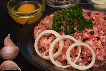 Raw meat beef in a plate with spices on a black cutting board. Fresh stuffing.