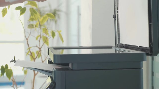 Close-up of woman using photocopier for document copying at office
