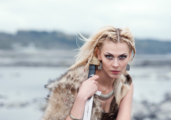A woman is a warrior in a wolf's skin with a sword in her hands. Girl of the Vikings. Reconstruction of the medieval scene.