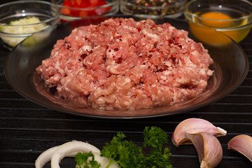 Raw meat beef in a plate with spices on a black cutting board. Fresh stuffing.