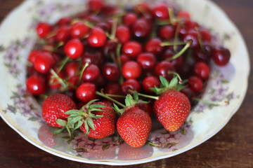 Strawberries and sweet cherries. Berries close-up on a plate