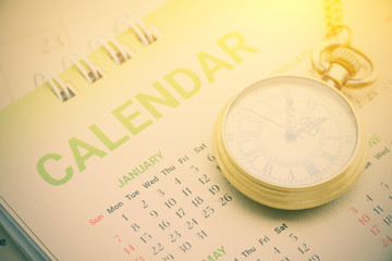 Calendar planner stationery concept : Pocket watch on a paper desk calendar. A calendar is a system of organizing days for commercial or administrative purposes by giving names to a period of time.