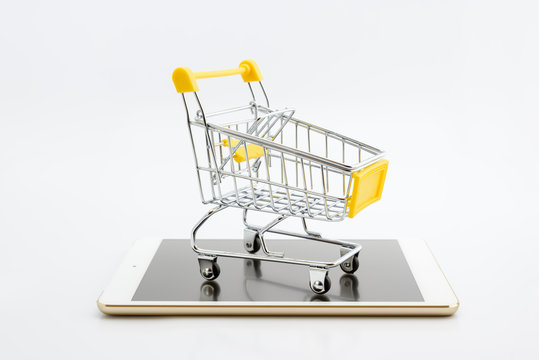 Online shopping with smart mobile device via internet concept : Empty yellow shopping cart on a white smart tablet. Online shopping gains more popularity today due to its convenience and time saving.