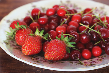 Strawberries and sweet cherries. Berries close-up on a plate