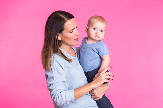 happy young mother with a baby child on pink background
