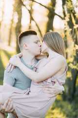 Fototapeta premium Beautiful young couple in the Park on a Sunny day, loving and happy. Walk and laugh. Pre-wedding shooting in nature. Casual style in clothing and European in processing