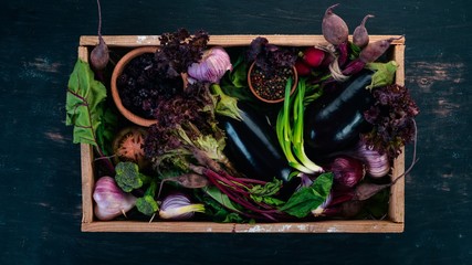 Purple food. Fresh vegetables and berries in a wooden box. On a wooden background. Top view. Copy space.