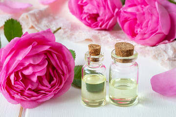Two bottles of essential oil with fresh roses