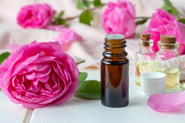 Obraz na płótnie Canvas A bottle of essential oil with fresh rose flowers