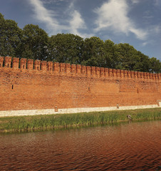 Fortress wall of red brick and moat with water.