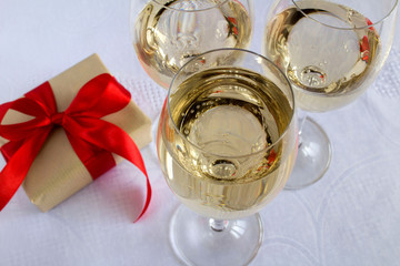 Champagne In the  glasses and gift on the white tablecloth.Top view.