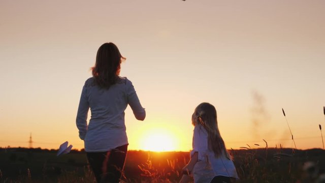 Mom and daughter launch paper airplanes into the air. Slow motion video