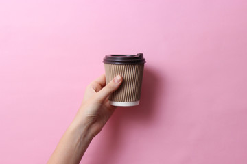 coffee in a cardboard glass in hand on a light background. minimalism, hot drinks.