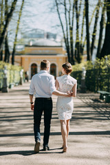 Fototapeta premium Beautiful young couple in the Park on a Sunny day, loving and happy. Walk and laugh together. Pre-wedding shooting in nature. Elegant style in clothes like celebrities