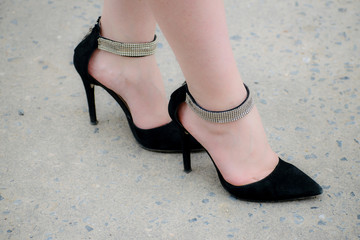 Long female legs in high heels in sparkling black shoes. Women's black suede shoes.