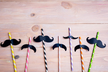Drinking straws for party on wooden background. Colorful paper disposable eco-friendly festive straws for cocktails. Drinking paper colorful straws with mustache.