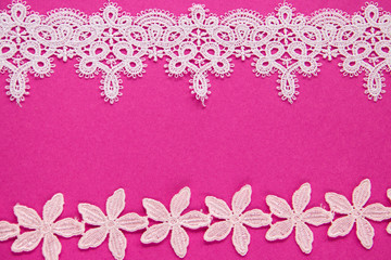 Fototapeta na wymiar Stripes of white lace on a pink background