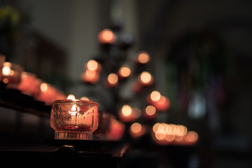 Opferkerze in Kirche, Spende, Lichtpunkte im Hintergrund