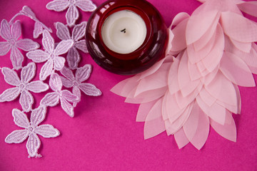 On a pink background azhurnre lace and a candle