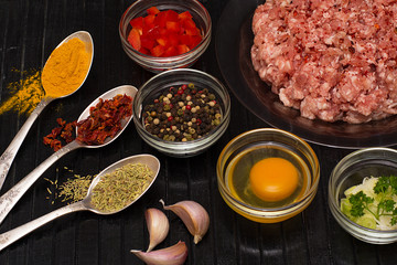 Raw meat beef in a plate with spices on a black cutting board. Fresh stuffing.