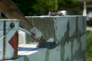 The process of bricklaying. Mason hands installing aerated concrete wall using special glue and...