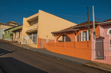 Working-class colored houses and fences in an empty street on a sunny day at São Manuel. A cute little town in the countryside of São Paulo State. Southeast Brazil.